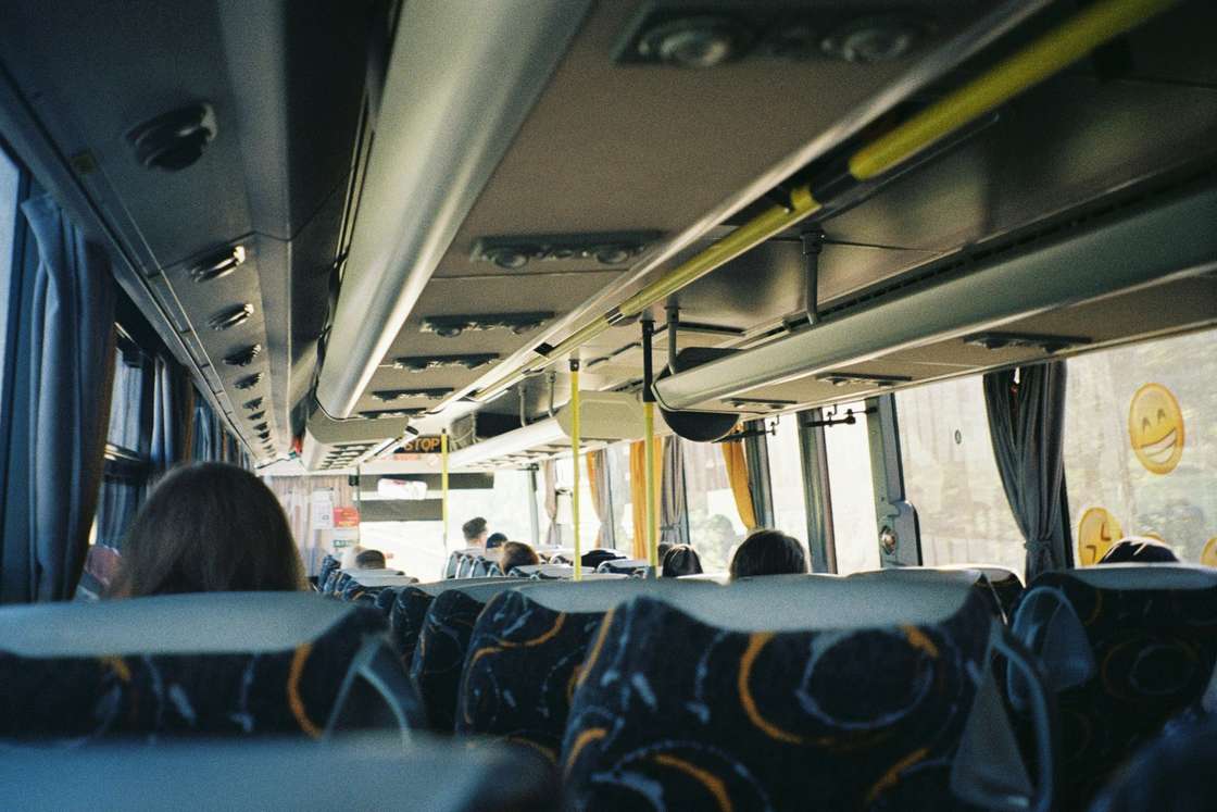 Inside a long-distance coach with passengers, seen from the back rows