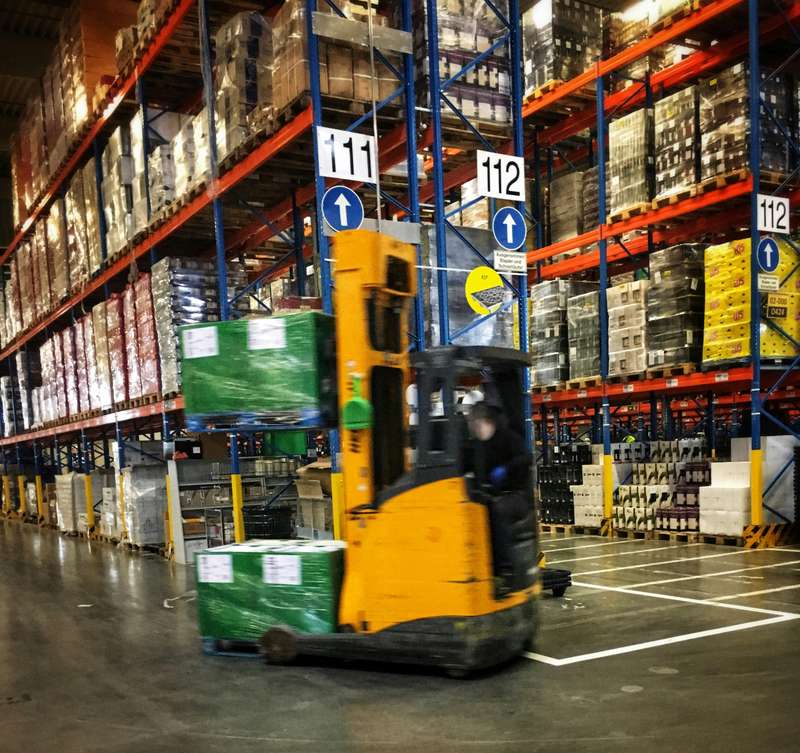 A forklift driving through a warehouse full of pallets