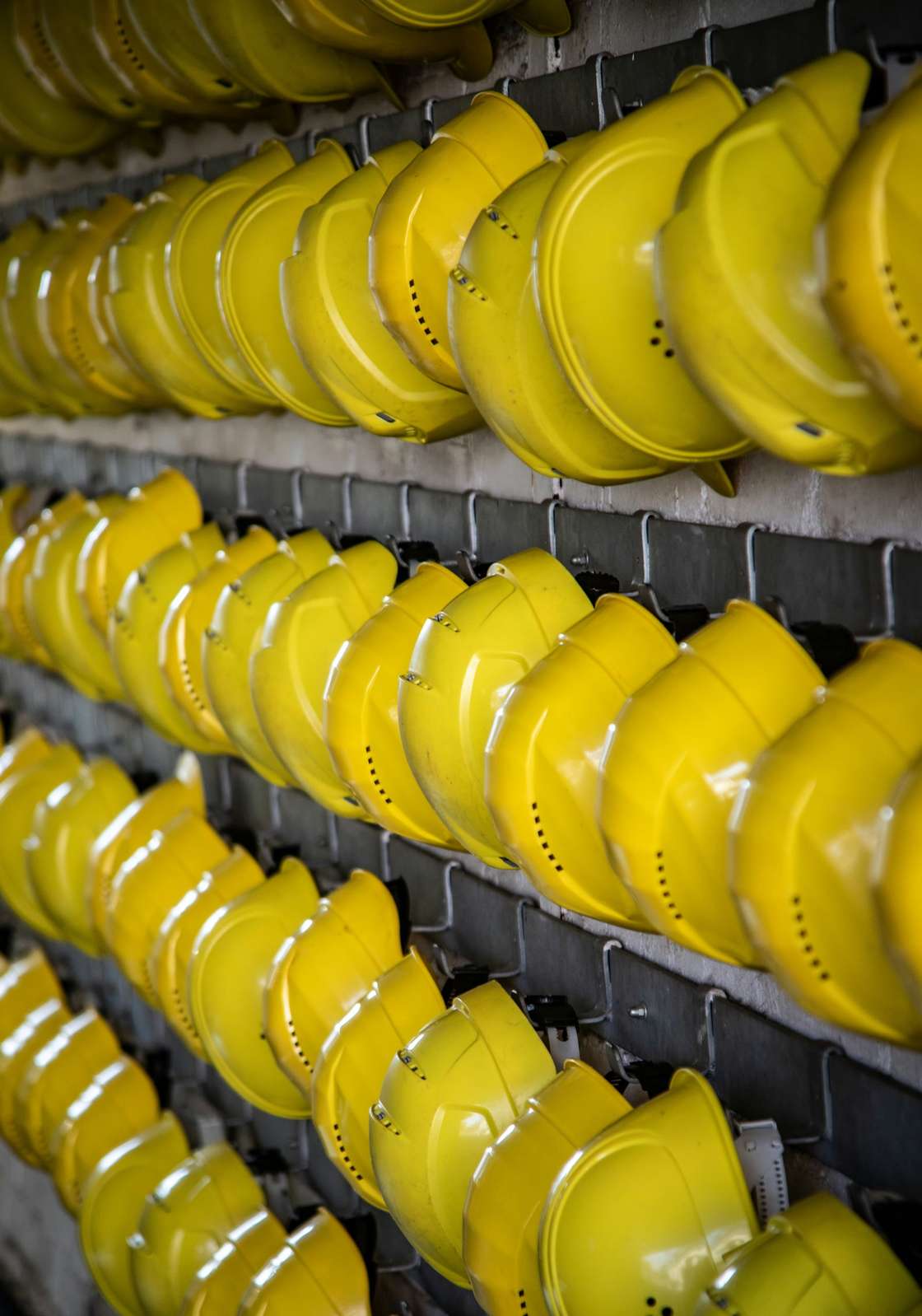 Rows of yellow safety helmets on hooks before a shift