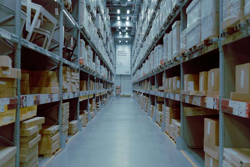 Narrow aisle in a warehouse with racks and cardboard boxes